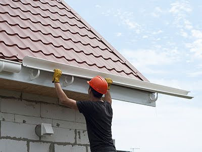 worker installs the gutter system on the roof